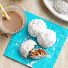 powdered donuts are sitting on a blue napkin next to a cup of coffee