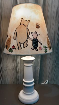 a lamp that is on top of a table with a bear and bee design on it