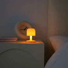 a small lamp sitting on top of a white nightstand next to a bed in a bedroom