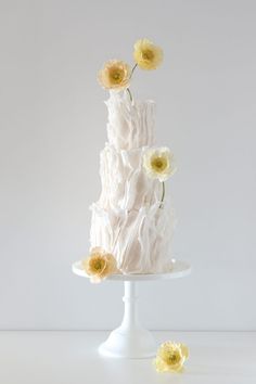 a three tiered white cake with yellow flowers on top