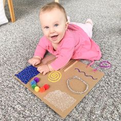 a baby is laying on the floor playing with beads and paper machs while smiling at the camera