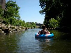 a boy is floating on an inflatable raft down a river