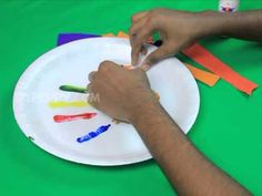 someone is painting on a paper plate with crayons