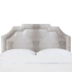 an upholstered bed with white sheets and pillows on the headboard is shown