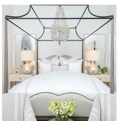 a bedroom with a white bed and chandelier over it's headboard