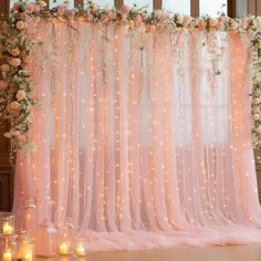 a pink wedding backdrop with flowers and candles