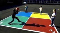 children playing basketball in an outdoor court with numbers painted on the floor and letters drawn on the ground