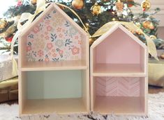 two wooden doll houses sitting in front of a christmas tree