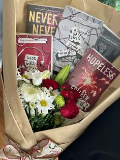 a bouquet of flowers and books in a paper bag