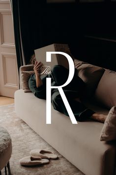 a person laying on a couch reading a book with the letter r in front of them