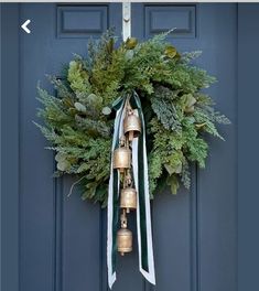 a christmas wreath with bells hanging from the front door and evergreens on the side