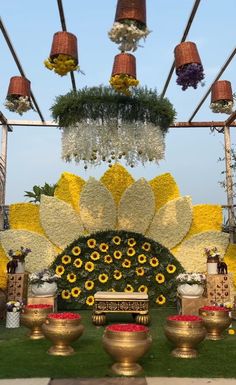 an outdoor ceremony with flowers and vases on the grass, hanging from metal poles