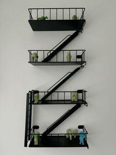 three black shelves with green and blue items on them in the shape of ladders