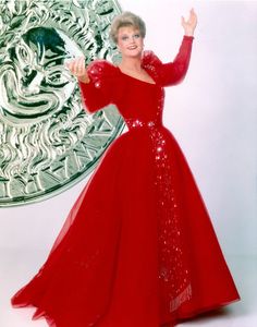 a woman in a long red dress is posing for a photo with her hand up