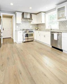 an empty kitchen with white cabinets and stainless steel appliances in the middle of the room