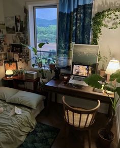 a bedroom with a bed, desk and laptop on the window sill in front of it