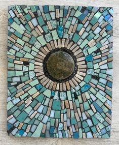 a mosaic tile wall hanging on the side of a wooden floor with a circular hole in it