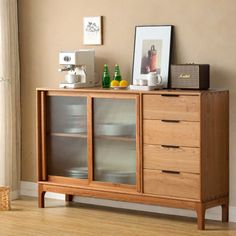 a wooden cabinet with glass doors and drawers in a living room next to a window