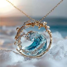 a necklace with a blue wave in the middle on top of some white sand and water