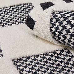 a black and white checkered blanket laying on top of a bed next to a pillow