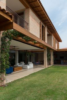 an outdoor living area with couches and tables on the grass next to a large brick building