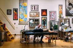 a man laying on top of a table next to a woman in a room filled with pictures