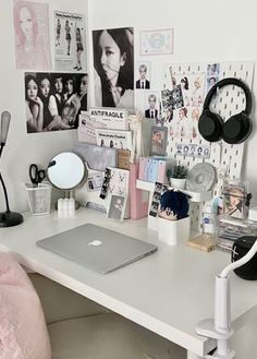 a white desk topped with a laptop computer and lots of pictures on the wall behind it