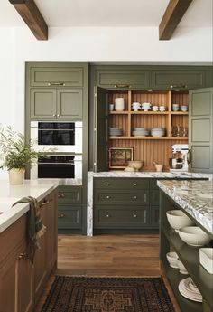 a kitchen with green cabinets and white counter tops on a rug in front of an oven