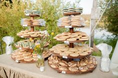 a table topped with lots of cookies on top of a wooden stand next to flowers