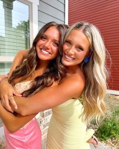 two beautiful young women standing next to each other in front of a red brick building