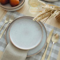 a table set with plates, silverware and pears