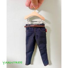 a hand holding a wooden hanger with a pair of jeans hanging from it's side