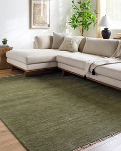 a living room with a large green rug on the floor and a white sectional couch