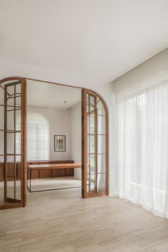 an empty room with wooden floors and large mirrors on the wall, along with white drapes