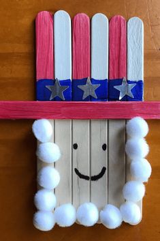 an american flag made out of popsicle sticks and pom - poms is hanging on the wall