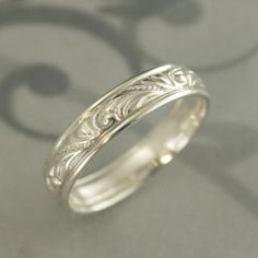 an intricately designed wedding ring sits on a table