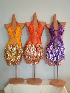 three mannequins with different colored sequins on top of each one