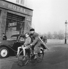 a man riding on the back of a bike next to a little boy in front of a hotel