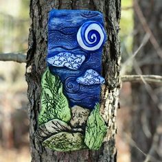 a blue and green piece of art on a tree