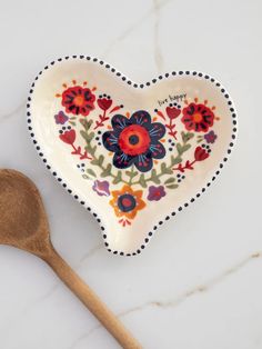 a heart shaped dish with flowers on it and a wooden spoon