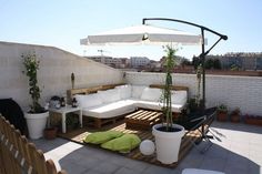 an outdoor living area with couches, tables and potted plants on the roof