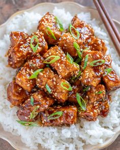 a plate full of chicken and rice with chopsticks