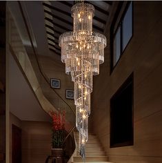 a large chandelier hanging from the ceiling in a living room with stairs leading up to it