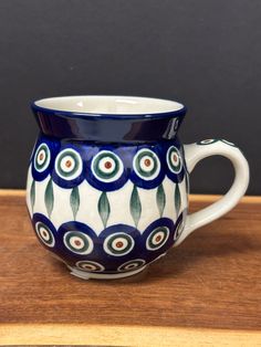 a blue and white coffee cup sitting on top of a wooden table