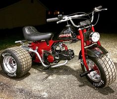 a small red motorcycle parked on top of a gravel road