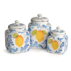 three blue and white canisters with fruit painted on them, one has an orange