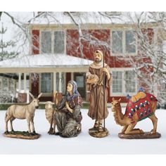 three nativity figurines in front of a house with snow on the ground