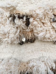 two sheeps are laying down on a white blanket with black and silver buttons in their eyes