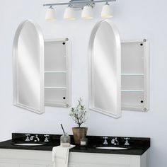 two mirrors on the wall above sinks in a white bathroom with black countertops and cabinets