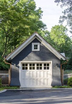 a gray house with white windows and a wooden fence around the front door is surrounded by trees